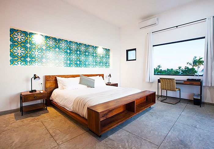 Bedroom with wooden bed, patterned headboard, desk, and large window overlooking trees.