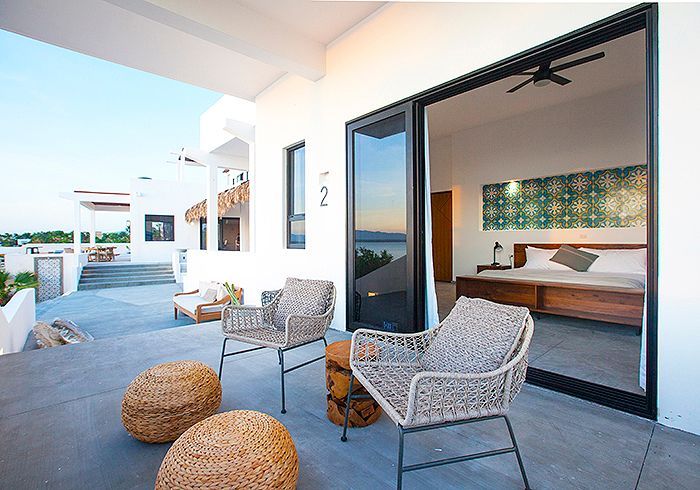 Patio with chairs and a view, leads to a bedroom with sliding glass doors.