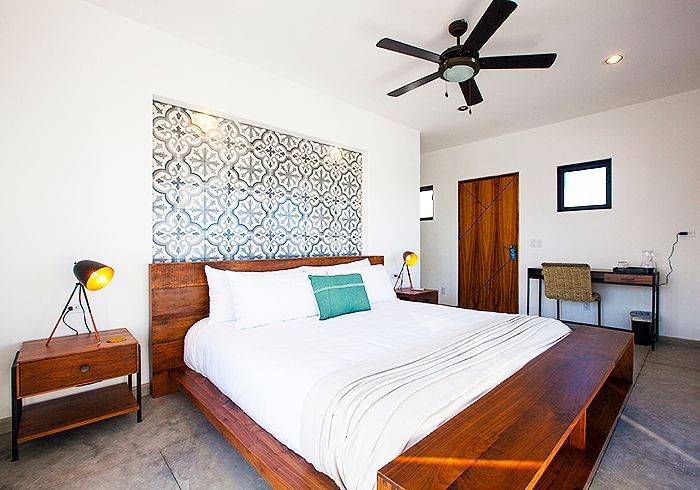 Bedroom with king-size bed, patterned headboard, wooden furniture, and ceiling fan.
