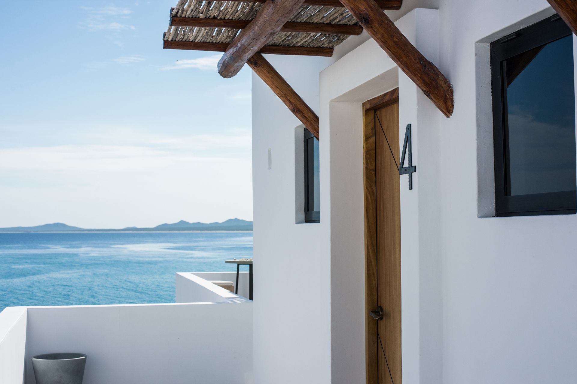 White building exterior with a door and windows overlooking a blue ocean.