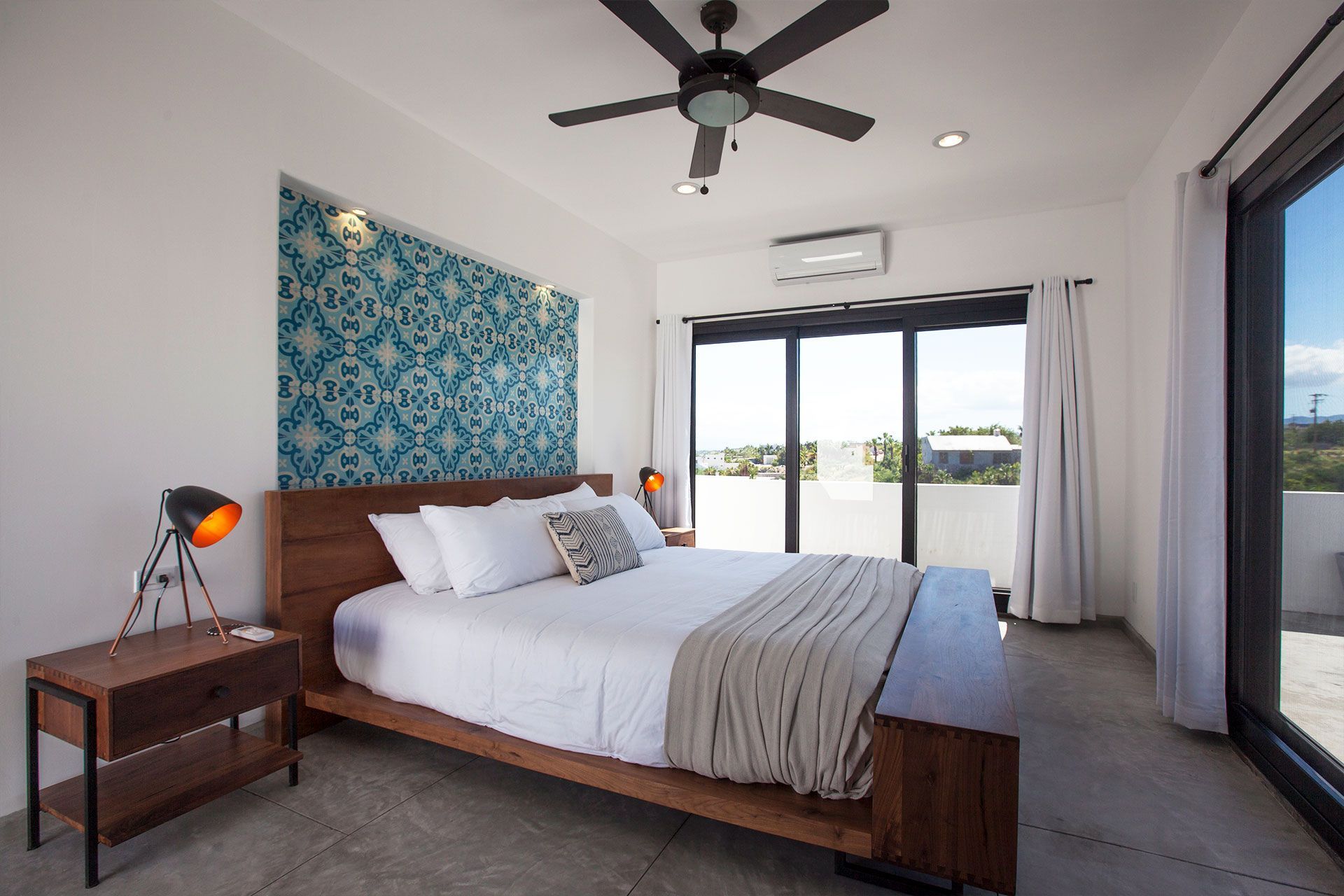 Bedroom with a wooden bed, patterned accent wall, sliding glass doors, and a ceiling fan.