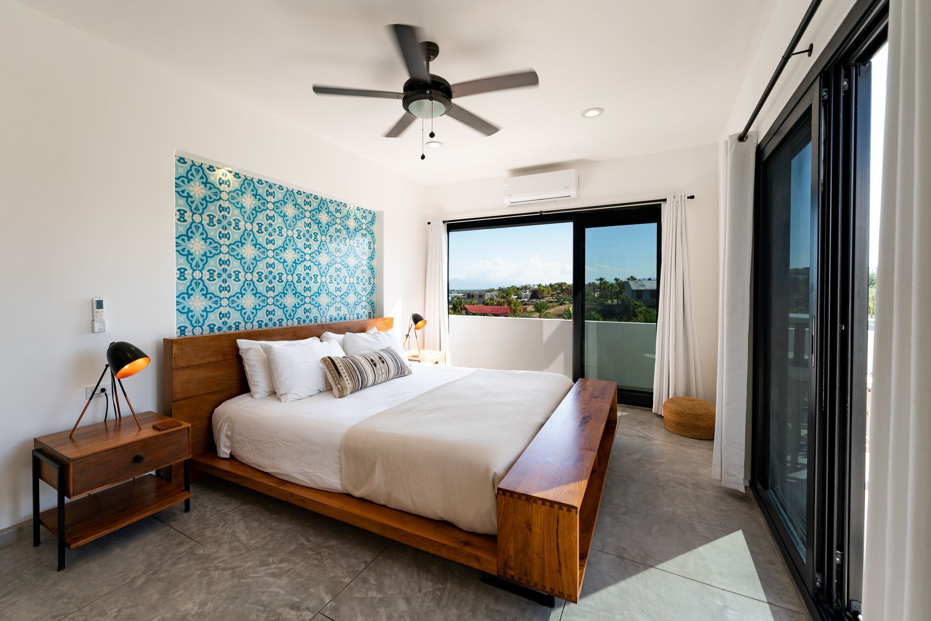 Bedroom with wooden bed, blue patterned wall, sliding glass doors, view.