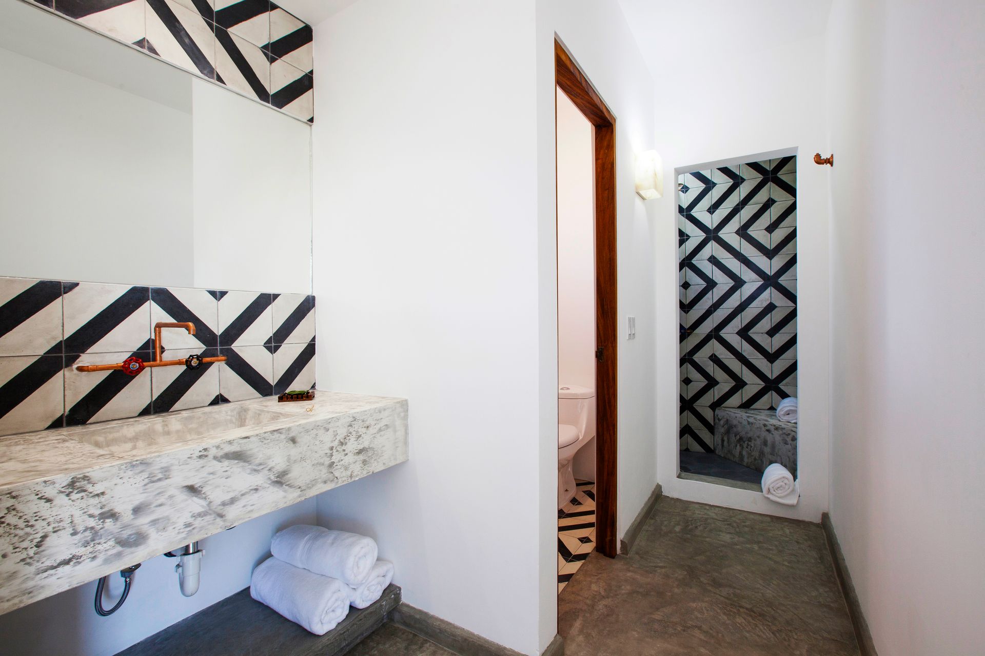 Bathroom with a geometric black and white tile design. White walls and marble countertop.