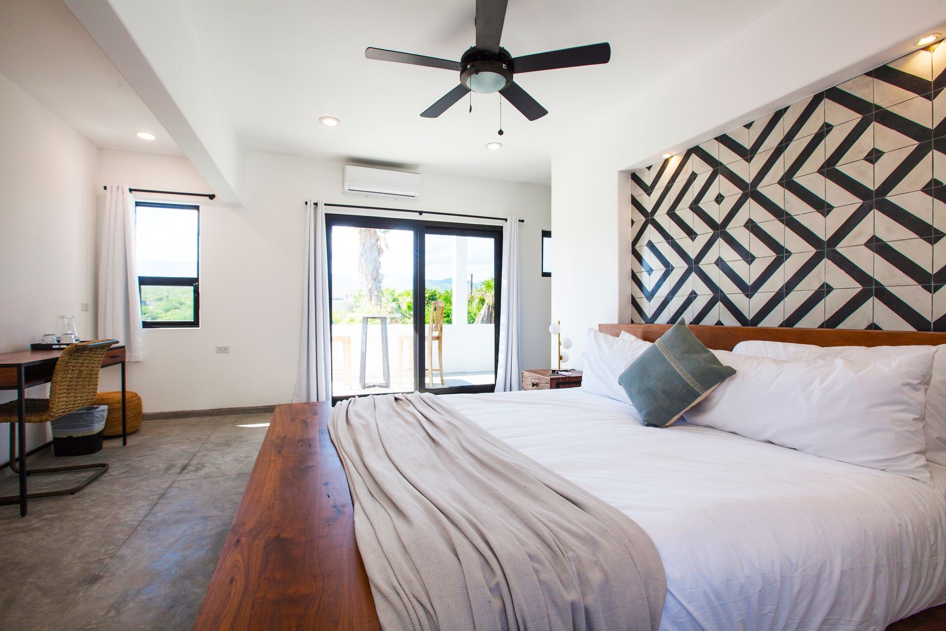 Bright bedroom with king bed, decorative headboard, and sliding glass door to a balcony.