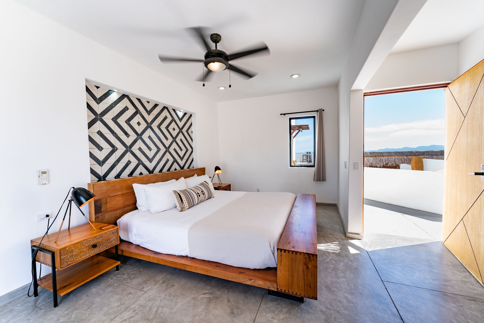 Bedroom with wooden bed, nightstand, and doorway to a patio with a view.