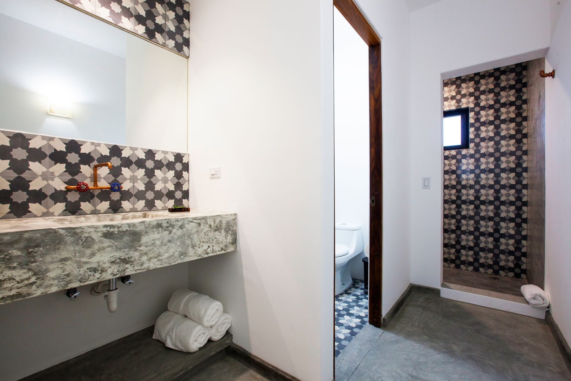 Bathroom with patterned tile accents, concrete sink, and doorway to a shower.
