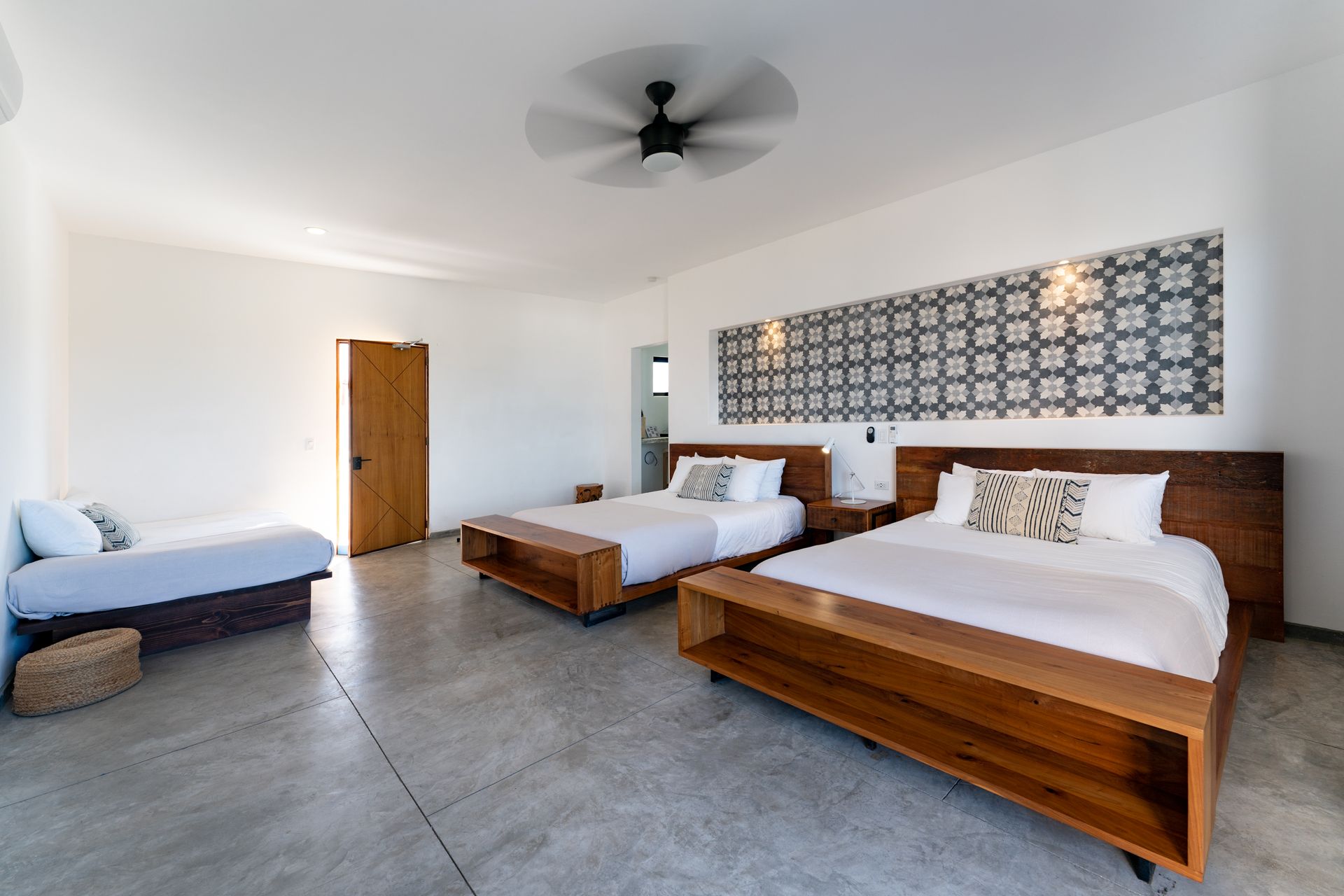 A modern bedroom with two beds, a daybed, and a decorative wall.