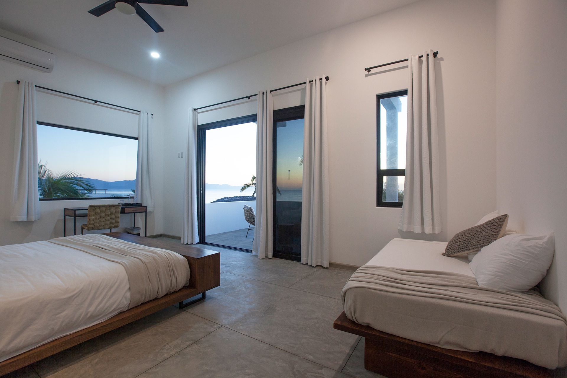 Bedroom with ocean view; two beds, large windows, sliding door to a balcony.