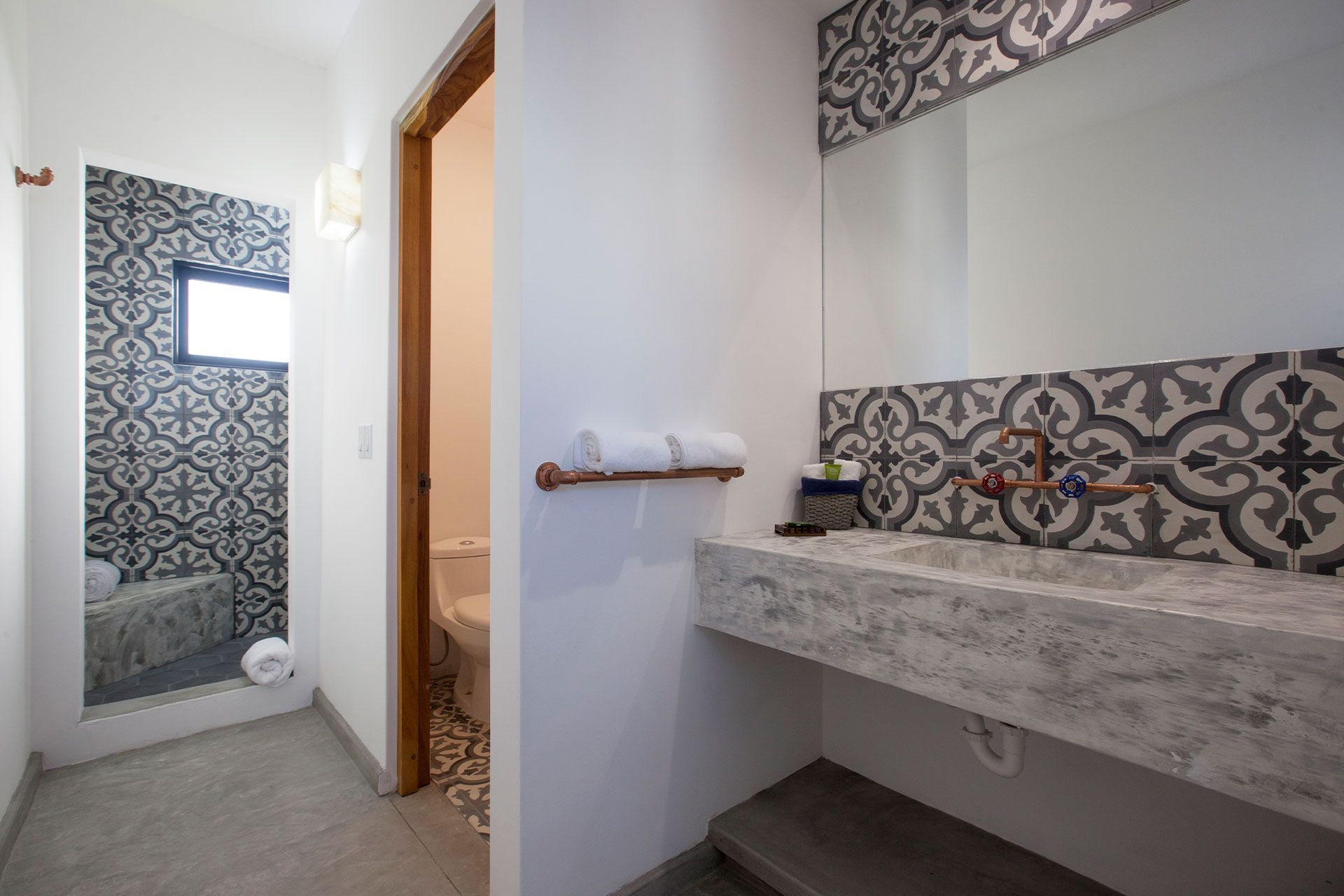 Bathroom with patterned tile, marble countertop sink, and a view into a shower stall.