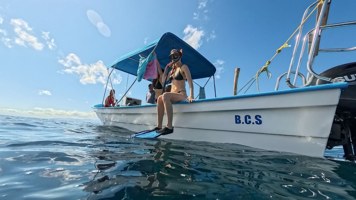 Woman on a boat, wearing snorkel gear. Blue canopy overhead. 