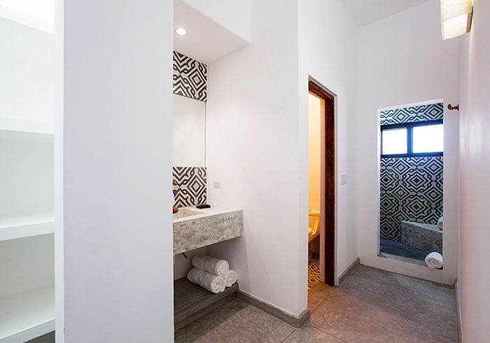 Bathroom with patterned tiles, granite vanity, and open doorway to another tiled area.