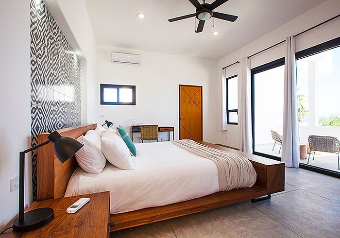 Bedroom with wooden bed, patterned accent wall, and sliding doors to a patio.