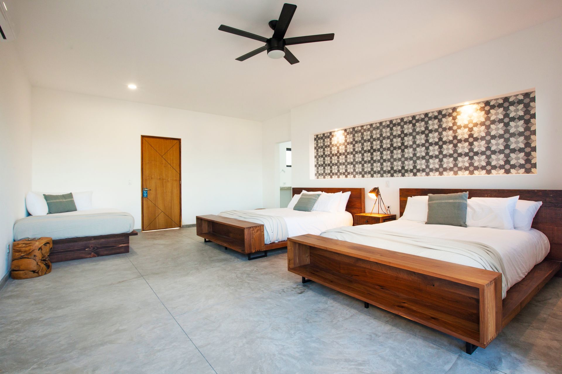 Spacious hotel room with two queen beds, a daybed, wood accents, decorative wall, and ceiling fan.