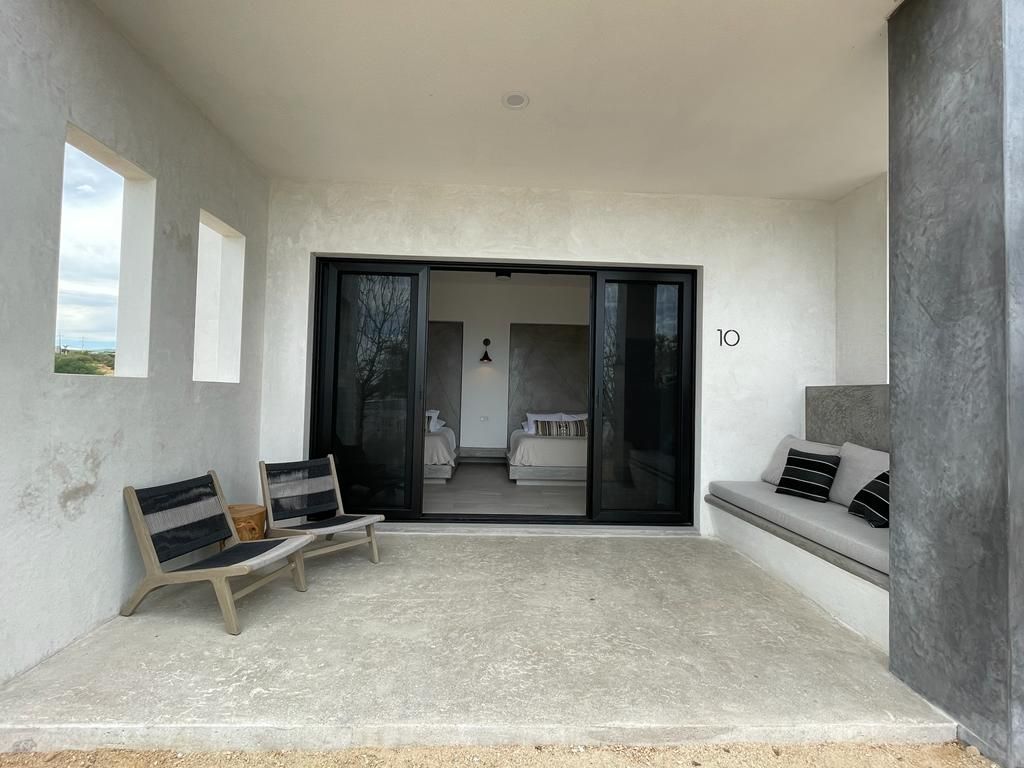 Patio with two chairs, built-in seating, and sliding glass doors leading into a room.