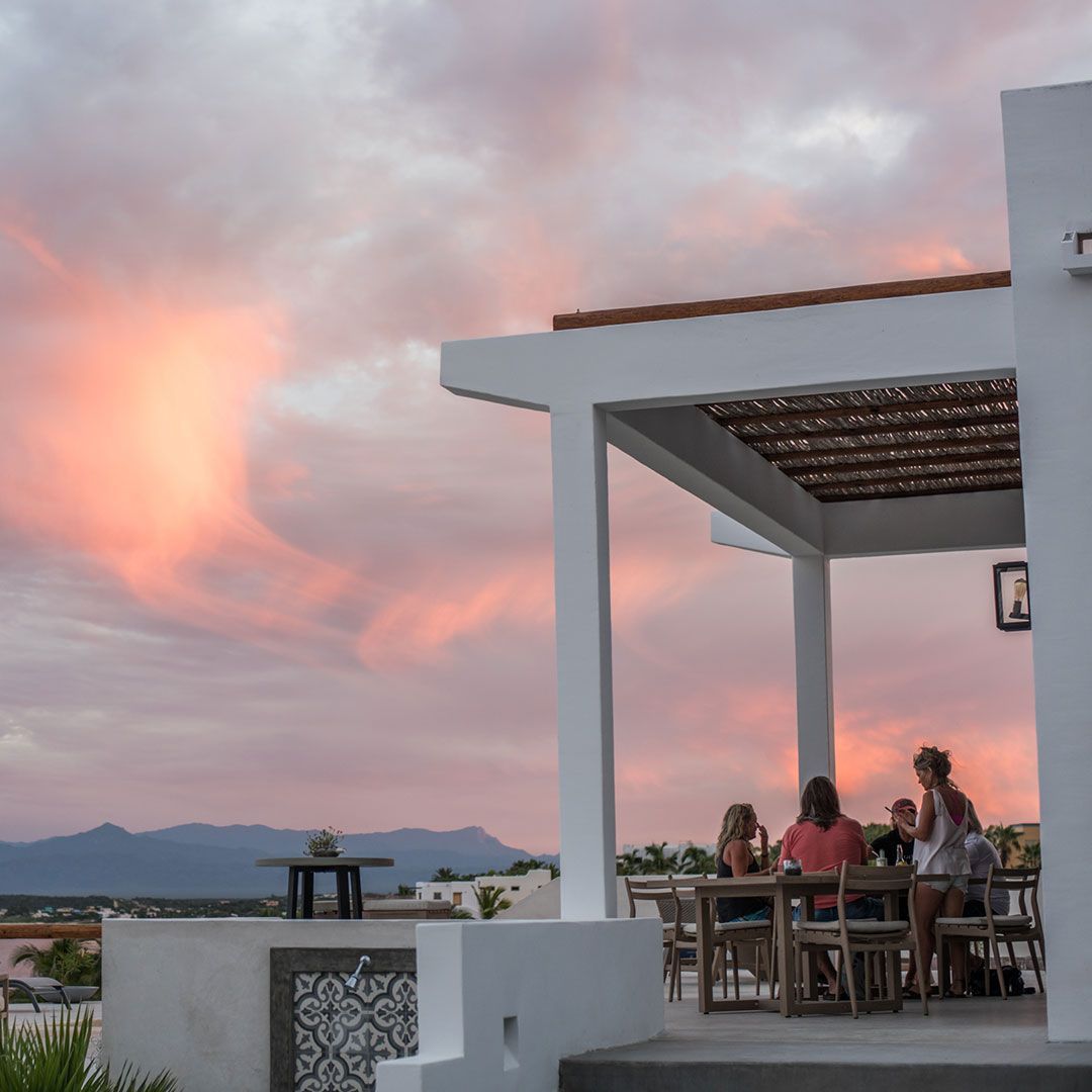 People at a rooftop patio with a sunset sky.