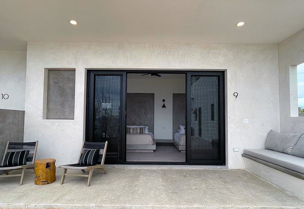 Patio with black sliding doors, two chairs, a stool, and built-in bench. The interior room is visible through the doors.