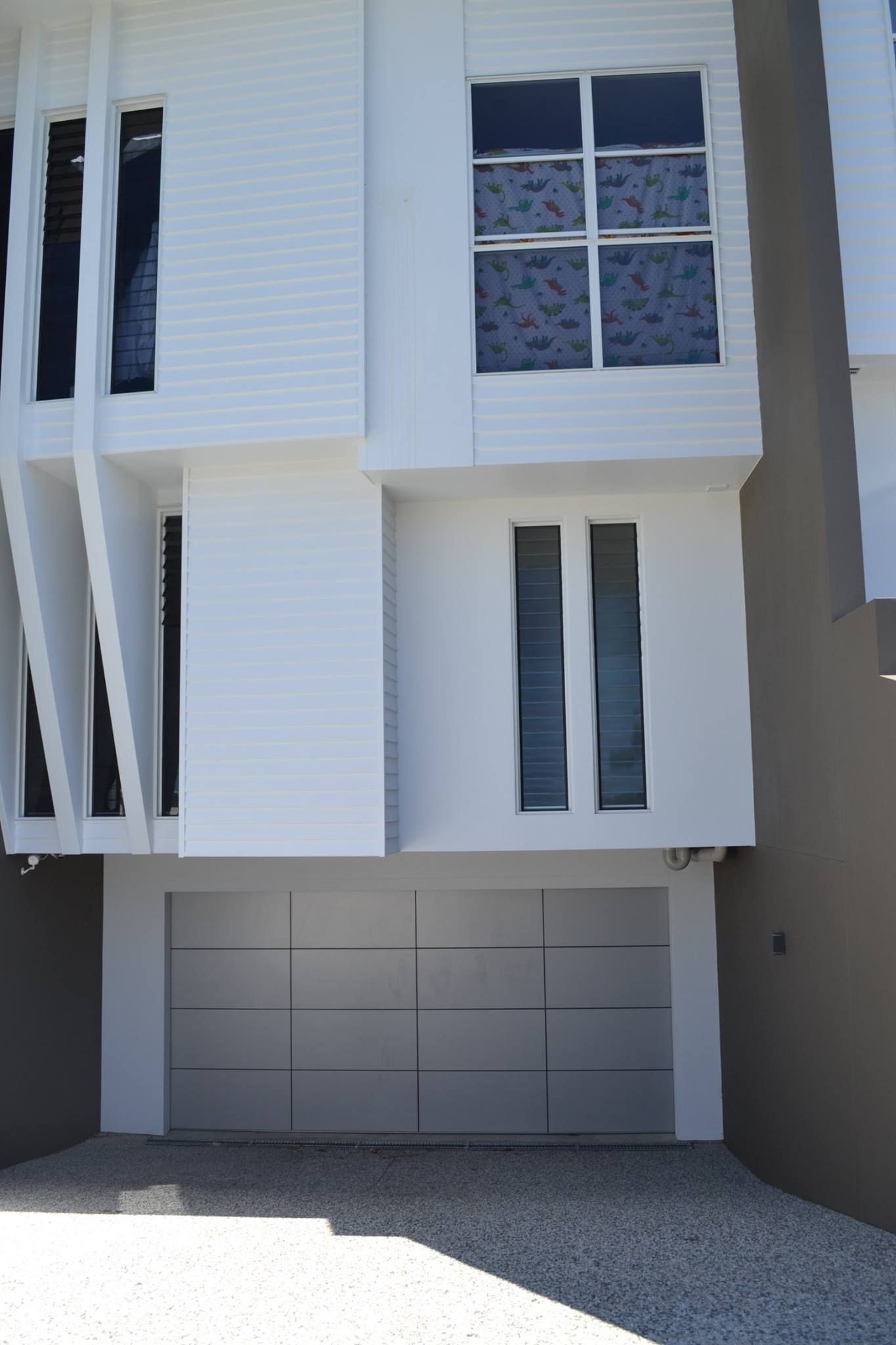 A White Building With A Garage Door And Two Windows — Gold Coast Door Centre In Burleigh Heads, QLD