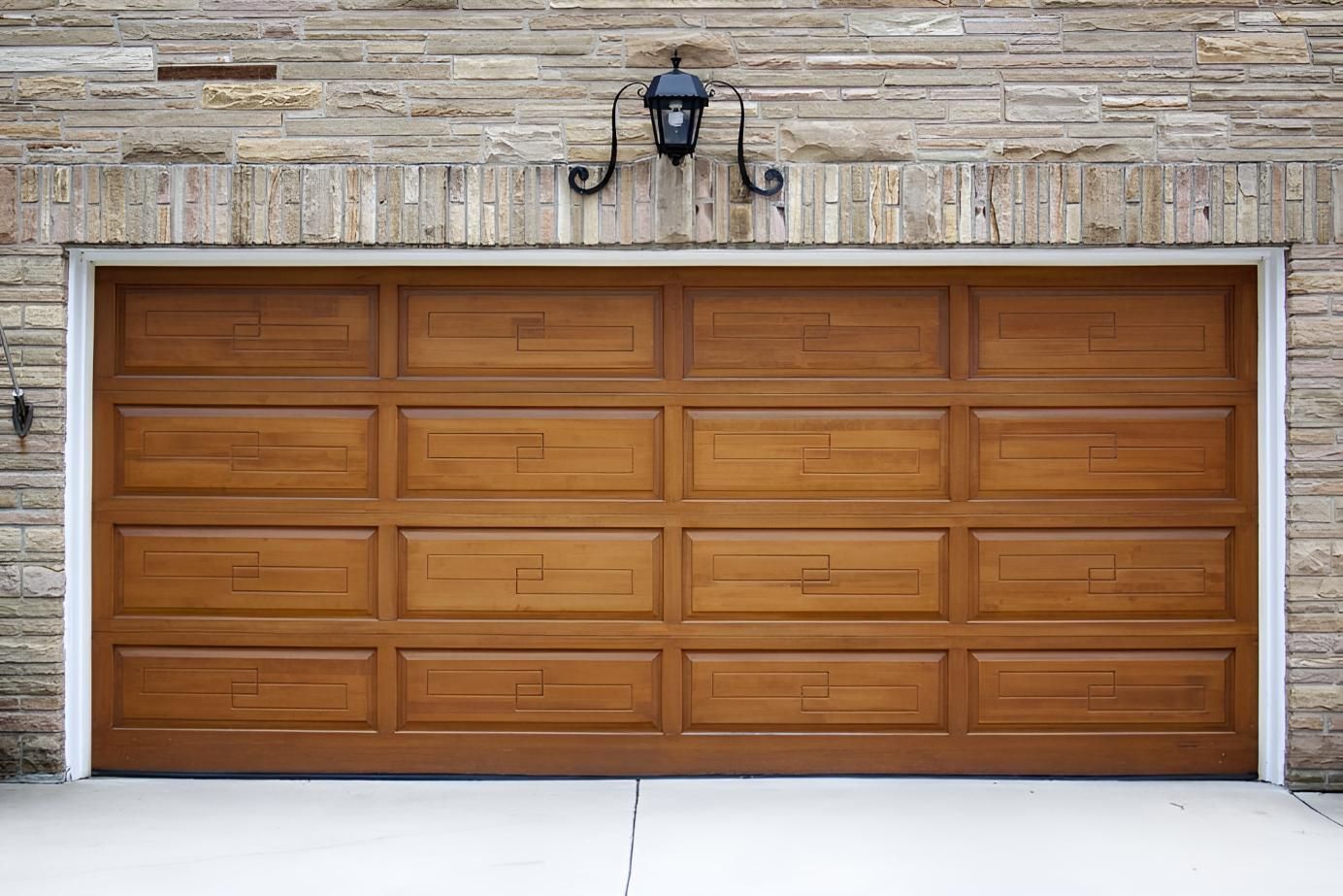 A Wooden Garage Door Is Sitting In Front Of A Brick Wall — Gold Coast Door Centre In Burleigh Heads, QLD