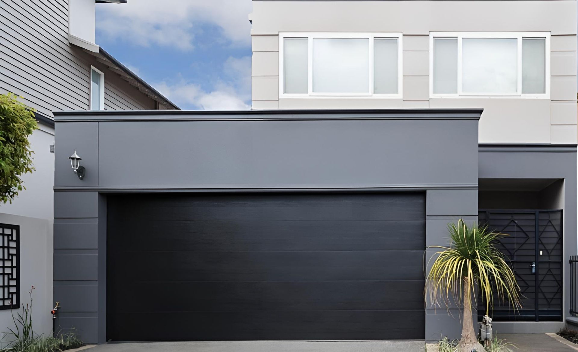 A House With A Black Garage Door And A Palm Tree In Front Of It — Gold Coast Door Centre In Burleigh Heads, QLD