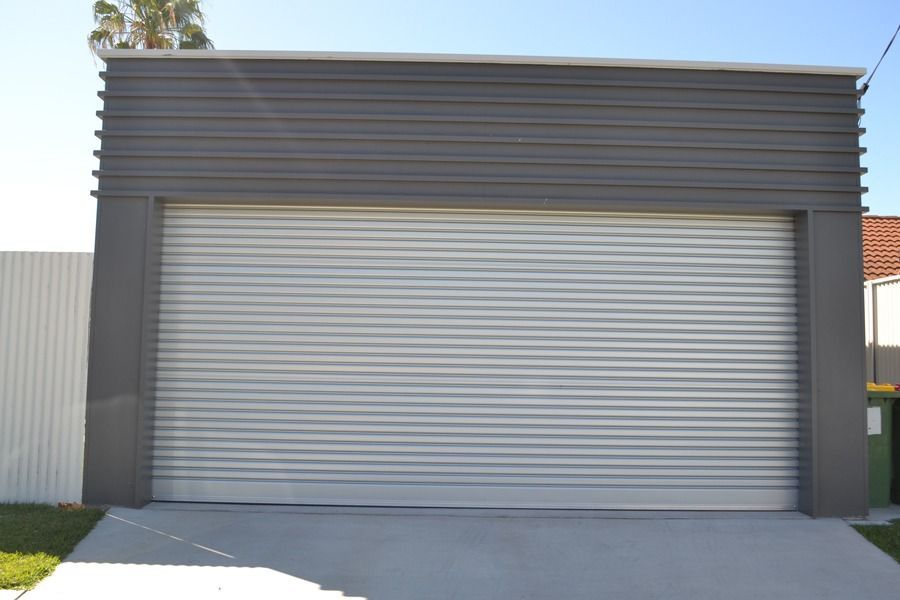 A Garage With A Gray Siding And A White Garage Door — Gold Coast Door Centre In Burleigh Heads, QLD