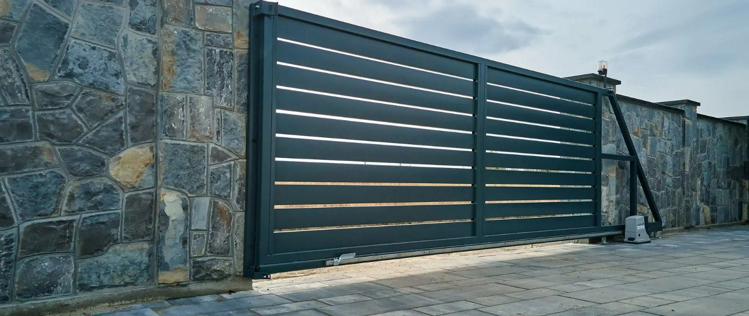 A Black Sliding Gate Is Sitting in Front of A Stone Wall  — Gold Coast Door Centre In Burleigh Heads, QLD