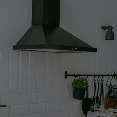 A black hood is hanging from the ceiling in a kitchen.