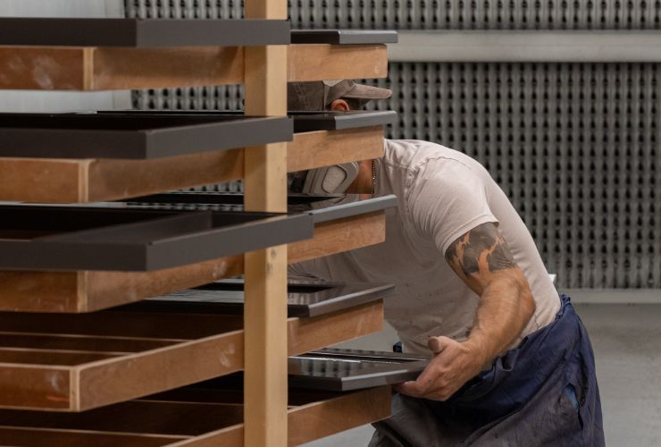 A man with a tattoo on his arm is working on a wooden shelf.