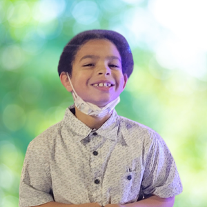 A young boy wearing a face mask is smiling.