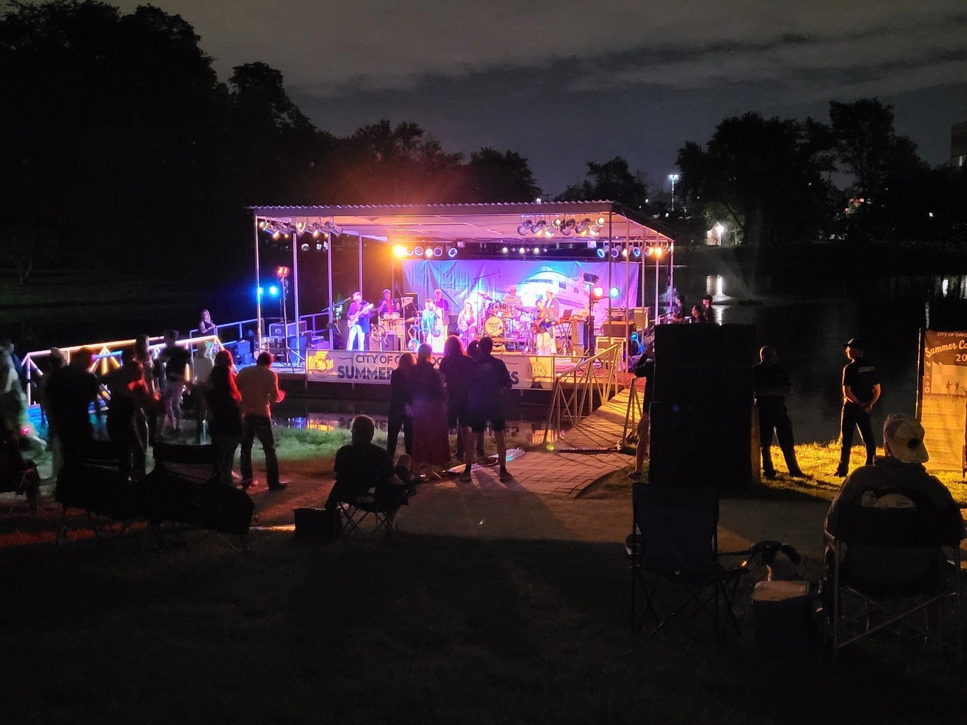 A group of people are standing in front of a stage at night.