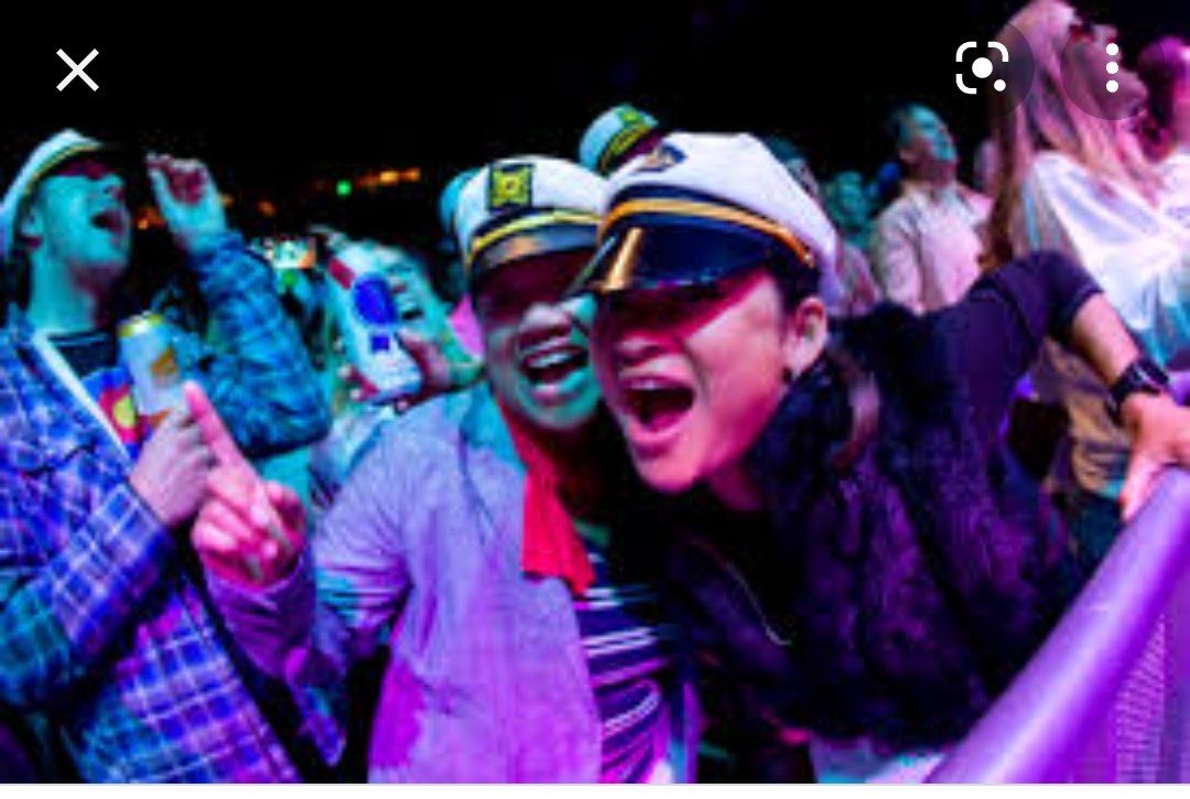 A group of people wearing captain hats are standing in a dark room