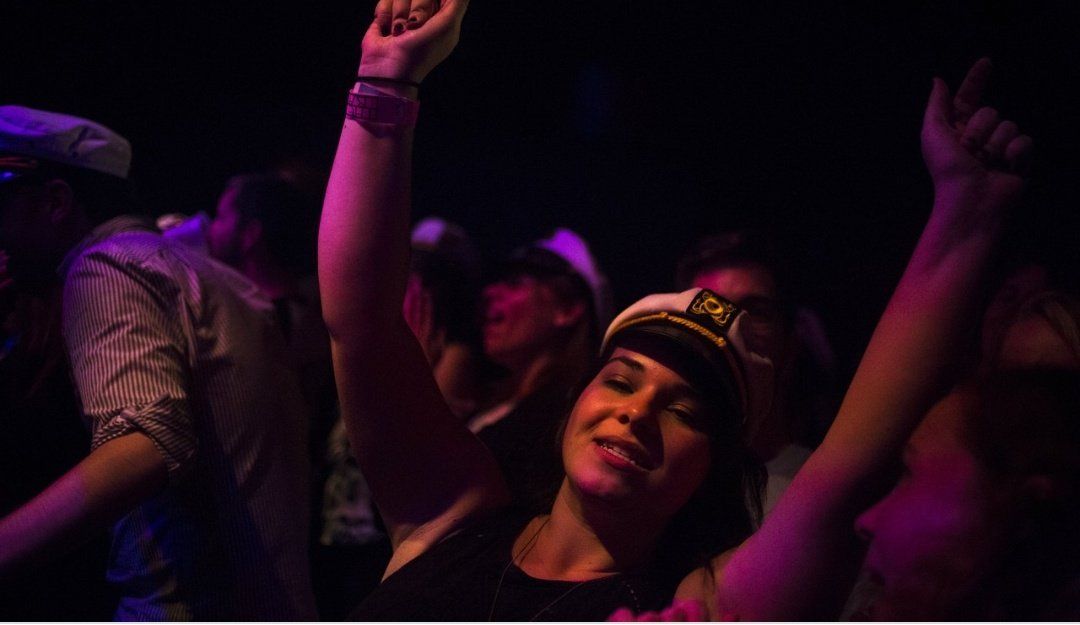 A woman in a captain 's hat is dancing at a party.