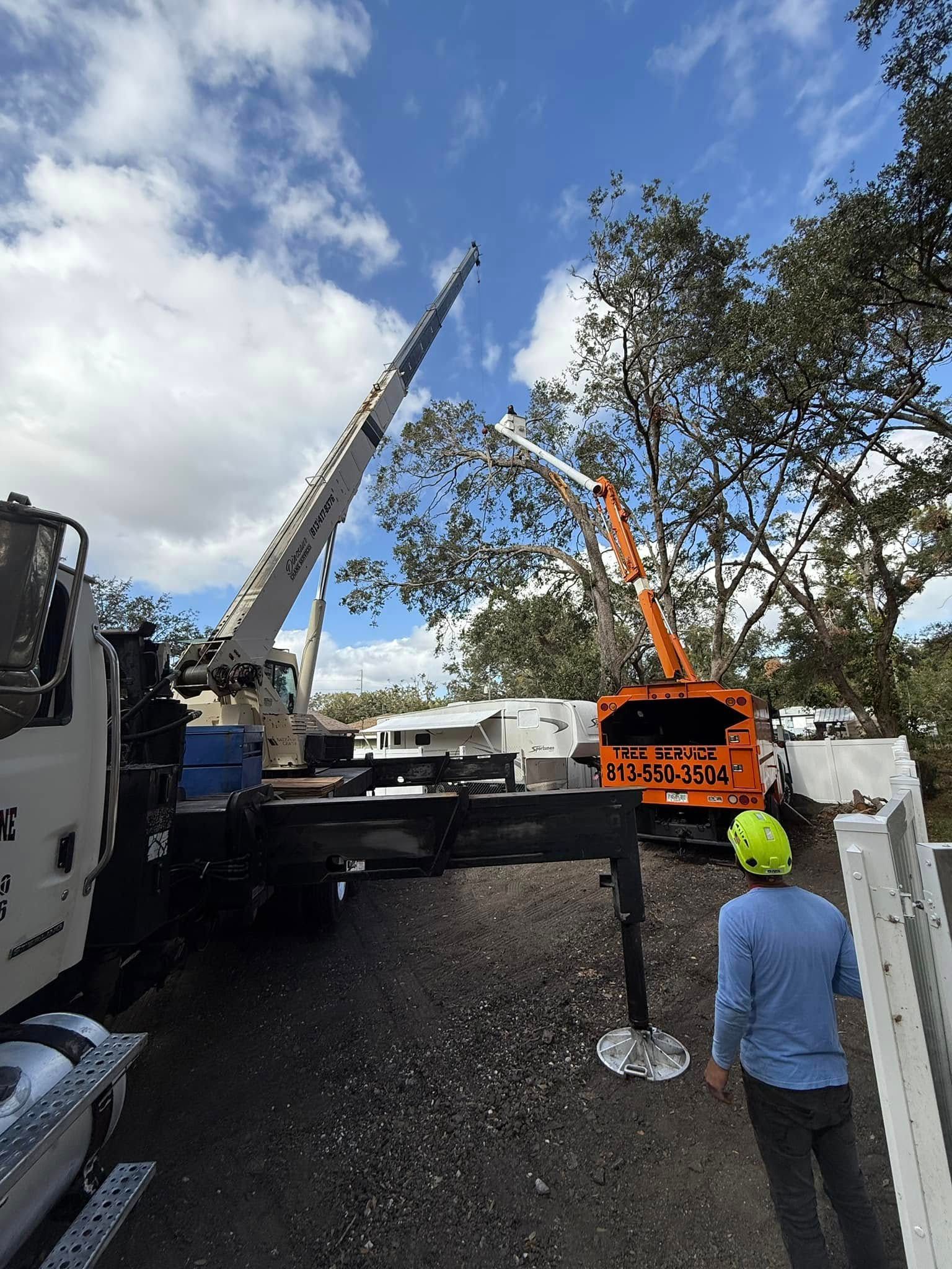 Two cranes lifting a heavy load on a construction site, with workers nearby under a cloudy sky