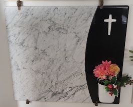 Una targa di marmo con una croce e dei fiori.