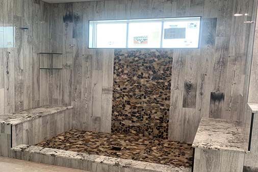 A bathroom with a walk in shower and a window.