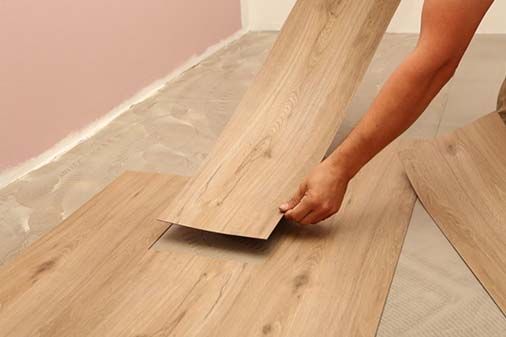 A person is installing a wooden floor in a room.