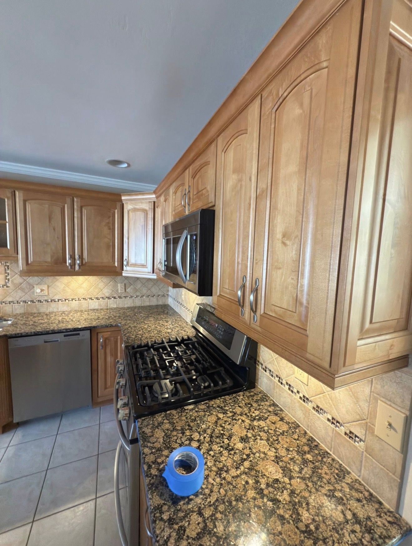 Kitchen with light wood cabinets, granite countertops, and stainless steel appliances.