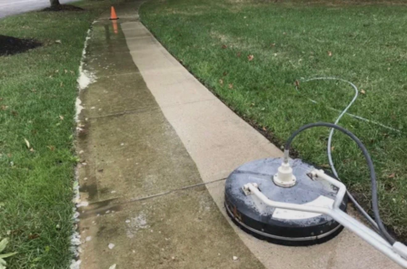 Power washer cleaning a concrete sidewalk, revealing a lighter, cleaner surface.