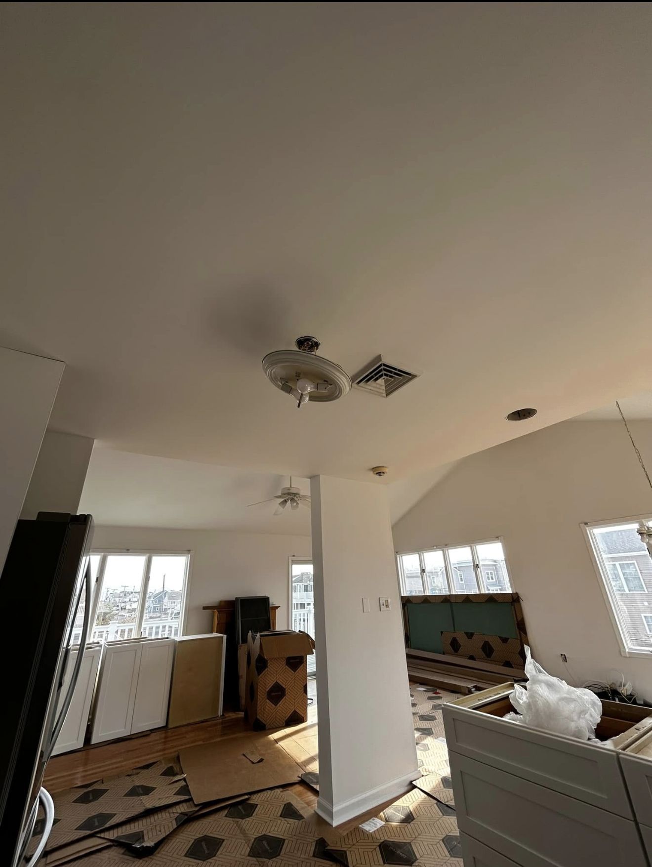 Interior during renovation; ceiling fan and exposed walls. Cluttered room with debris and open doorway.