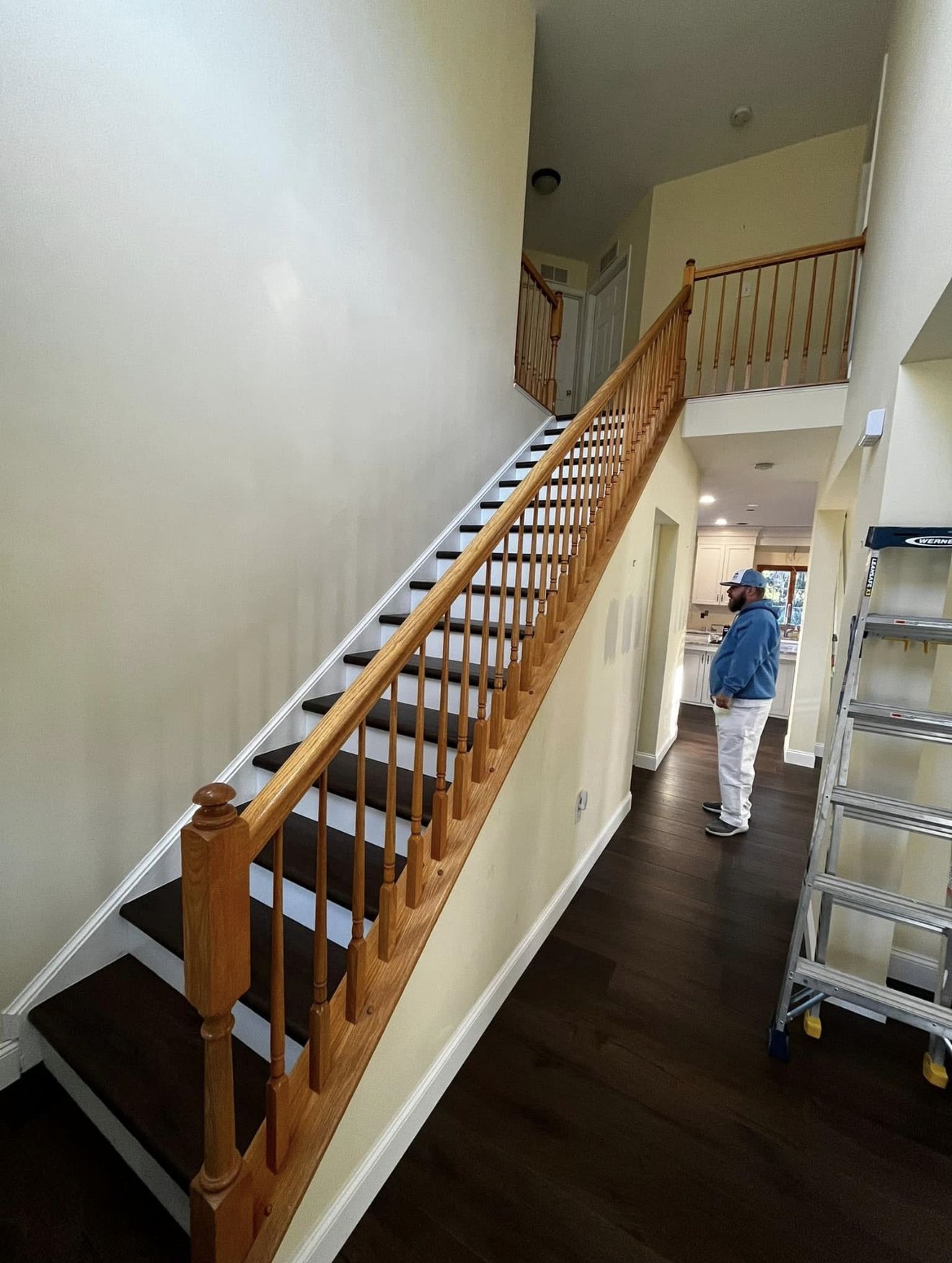 Interior view of a staircase with wood railing, dark steps, and a person standing on the landing.