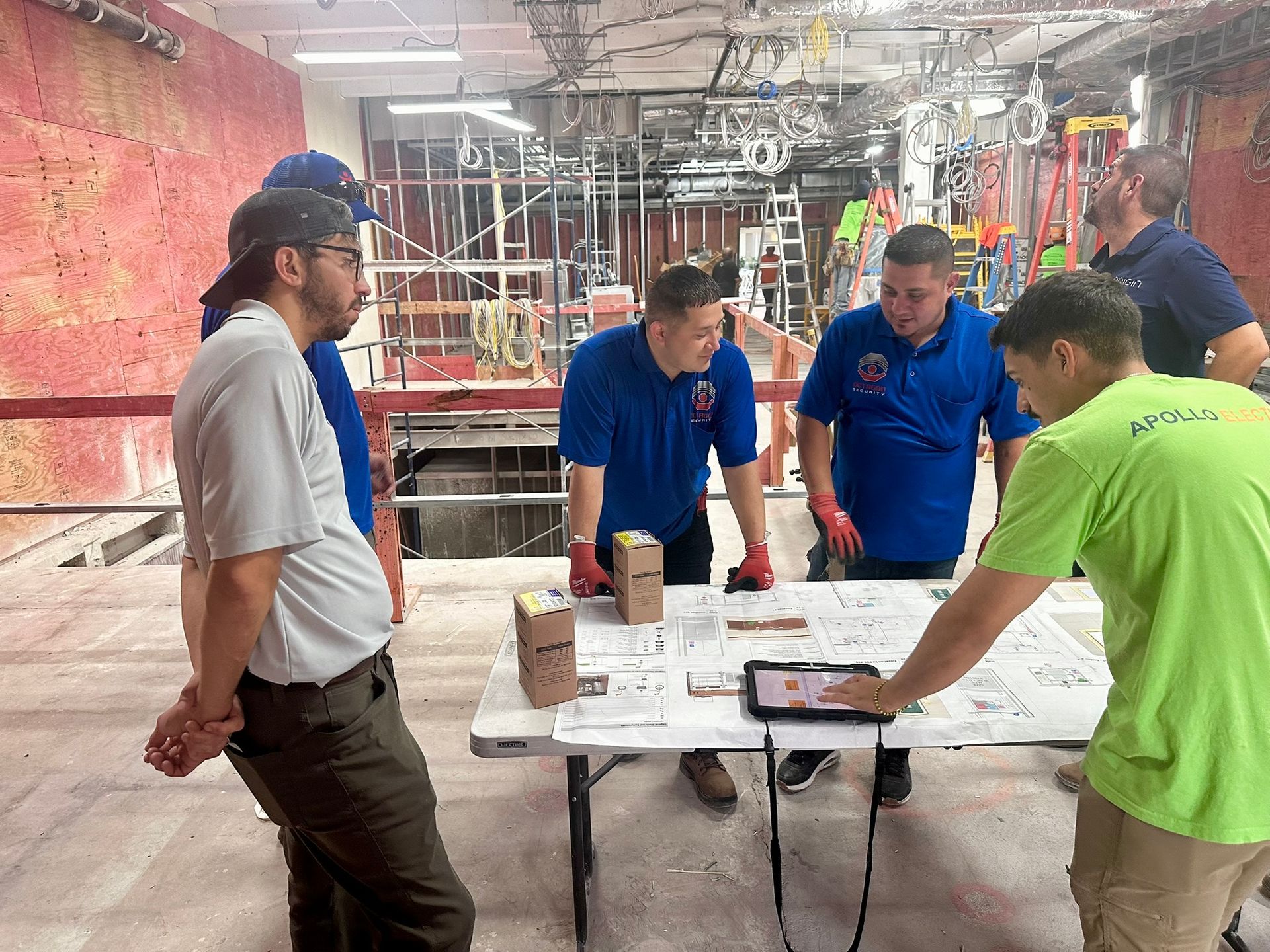 Construction workers reviewing blueprints at a table in a building under construction.