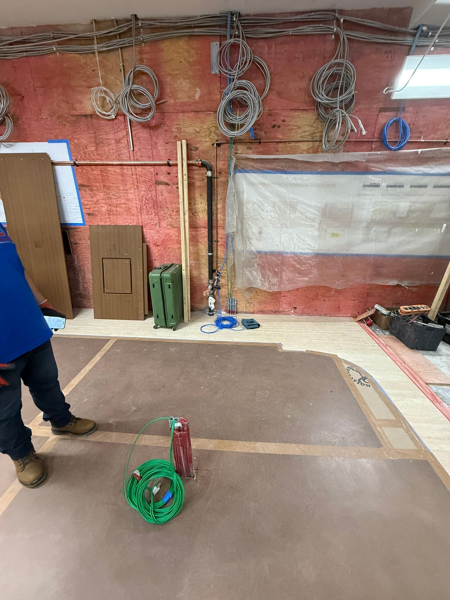 A person near a construction site with tools, cables, and a partial floor.