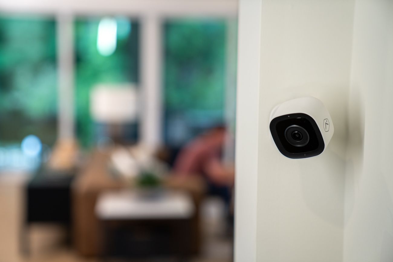 White security camera mounted on a dark building wall, angled toward the right.