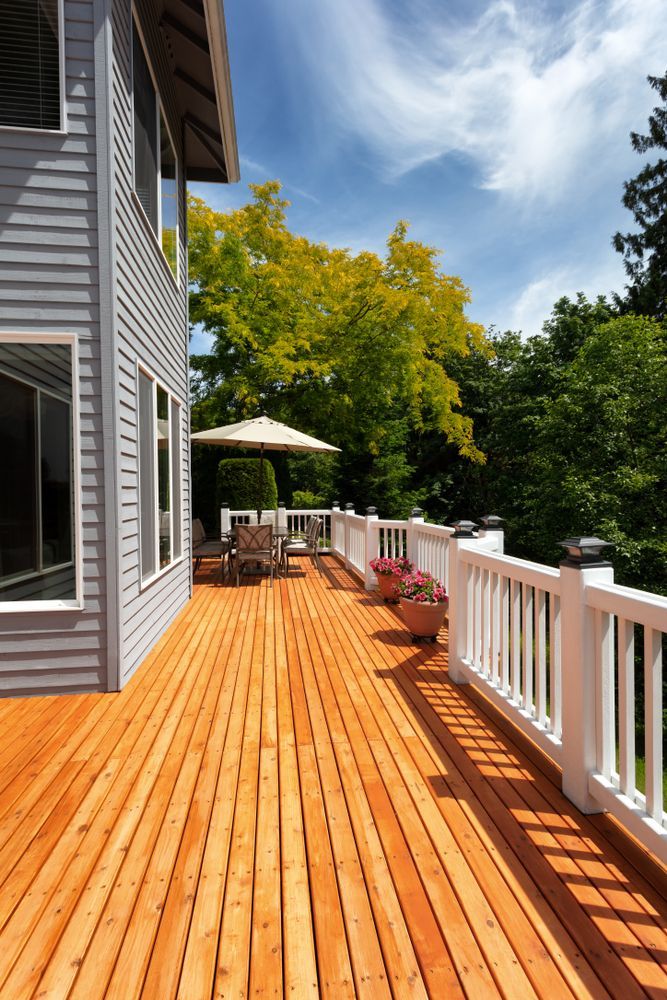 A large wooden deck with a white railing in front of a house.