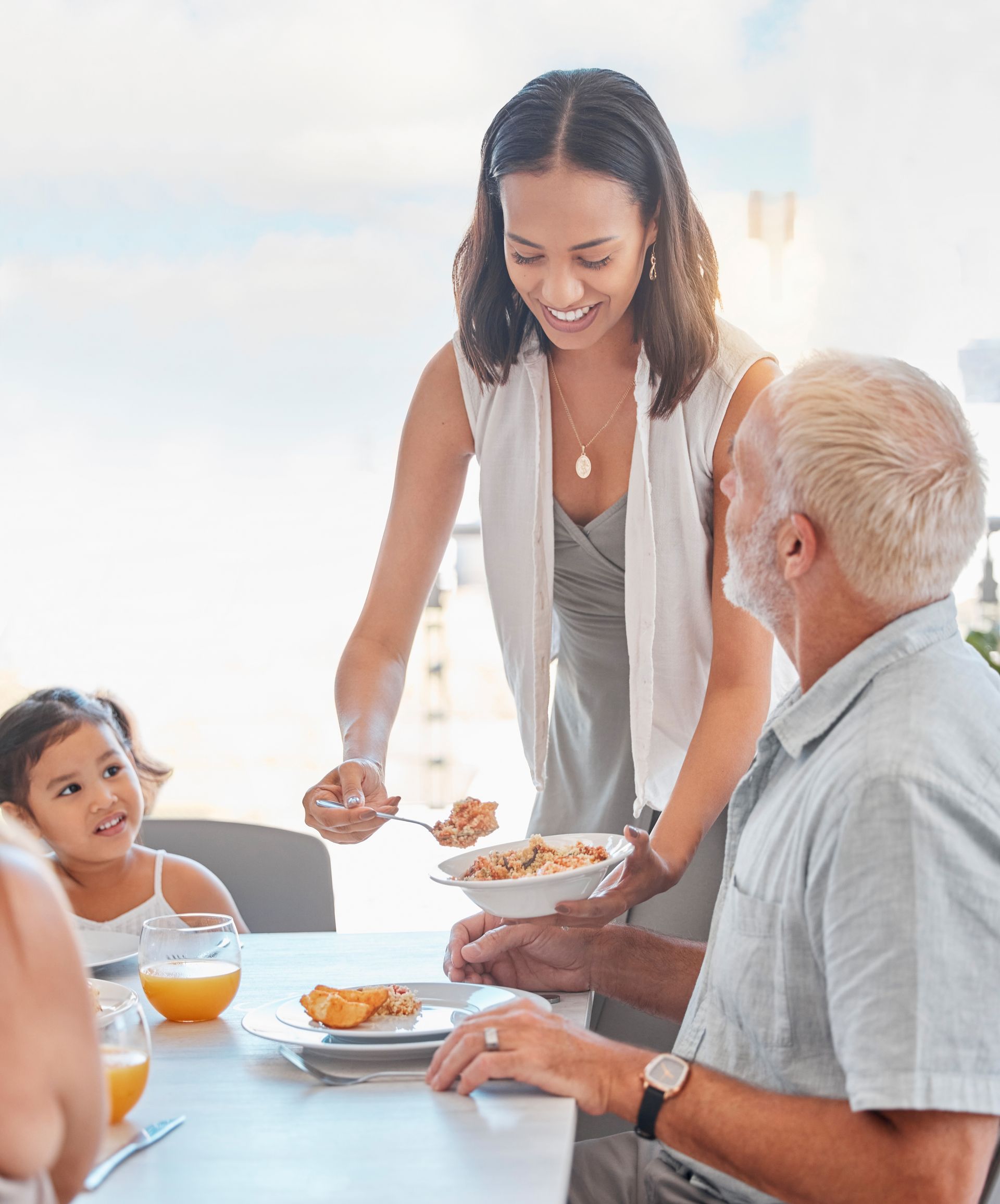 A woman is serving food to a group of people at a table.