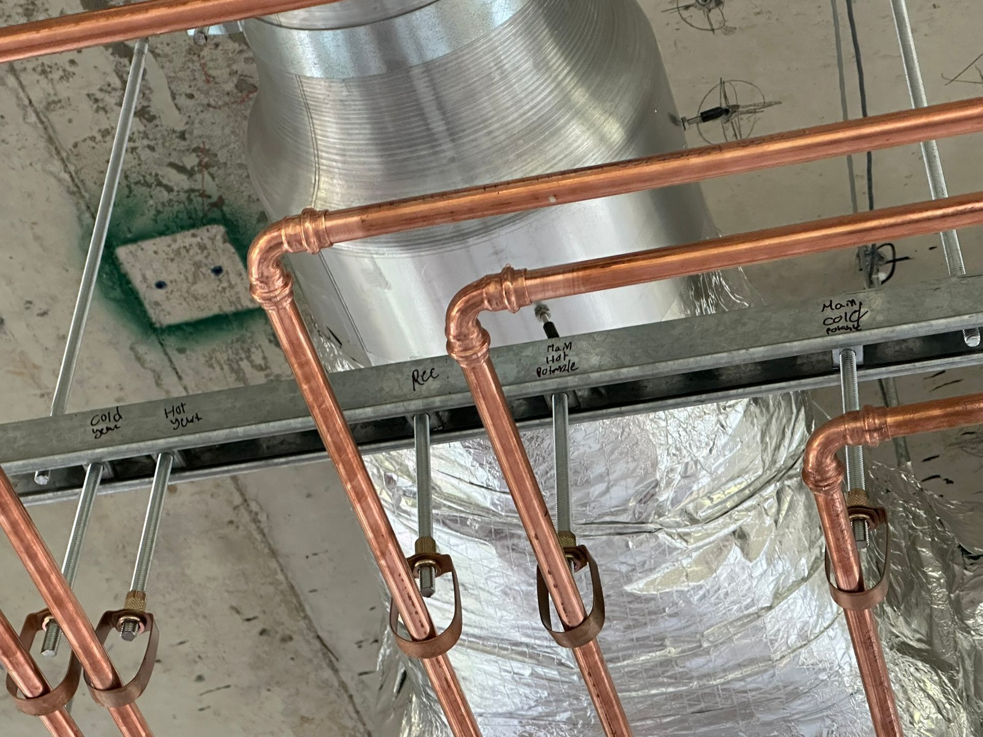 Des tuyaux en cuivre sont suspendus au plafond d'un bâtiment.