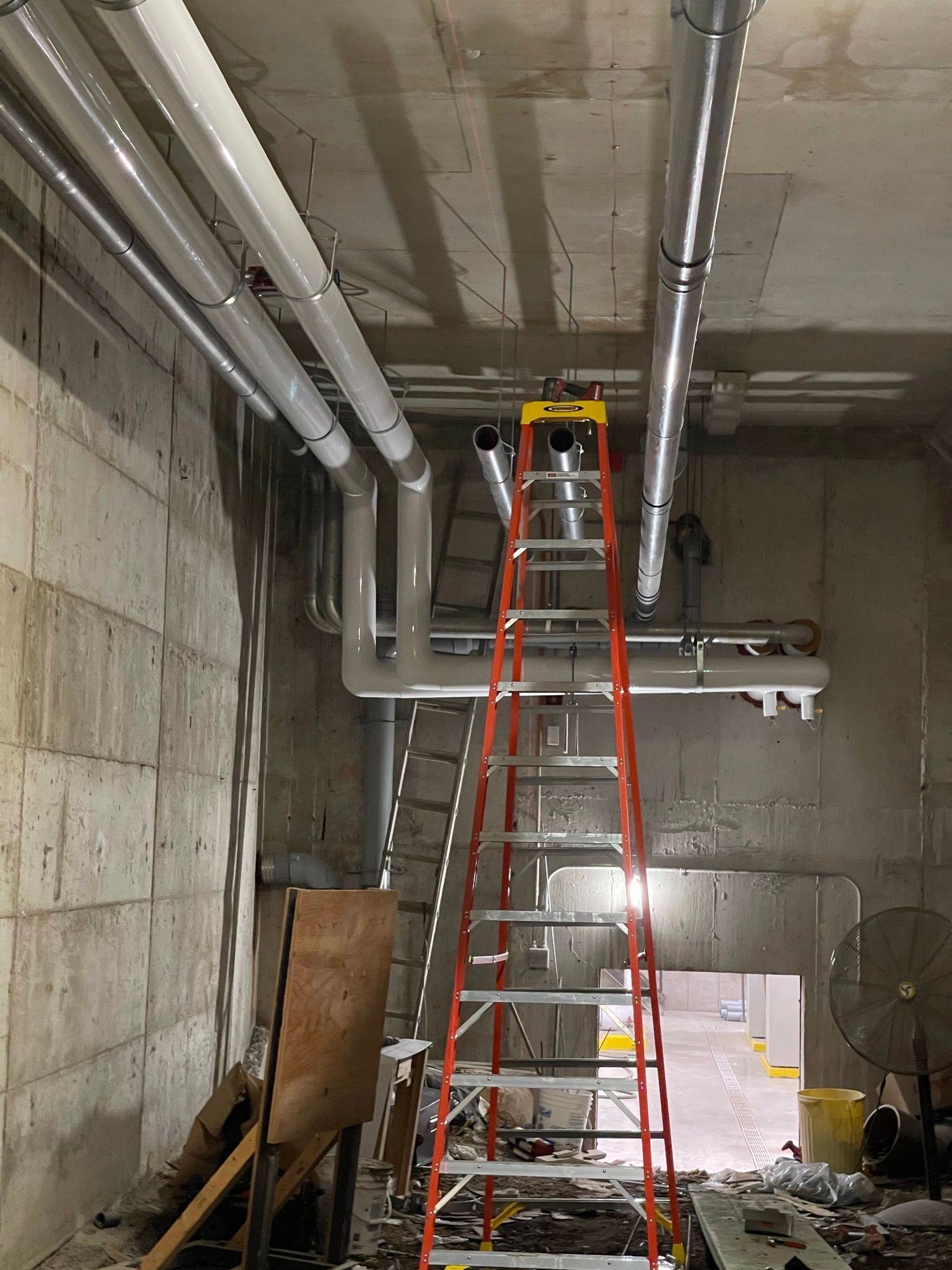 Un bâtiment en construction avec beaucoup de tuyaux suspendus au plafond.