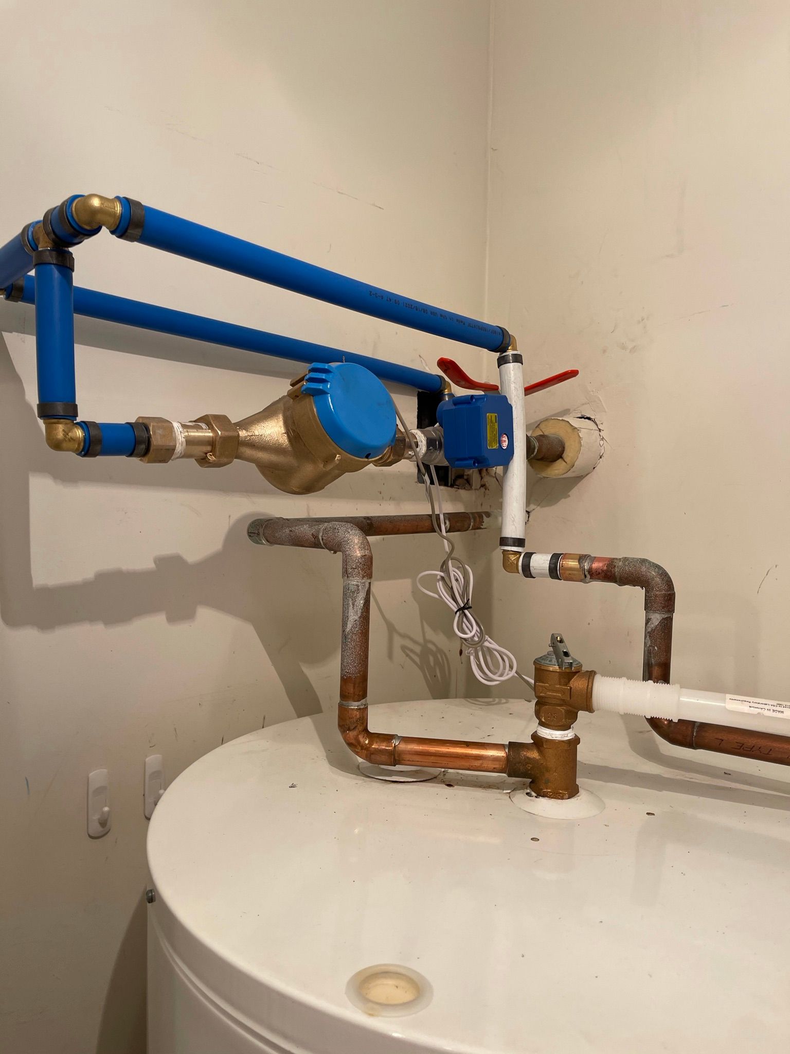 Un gros plan d'un chauffe-eau avec des tuyaux qui y sont attachés.