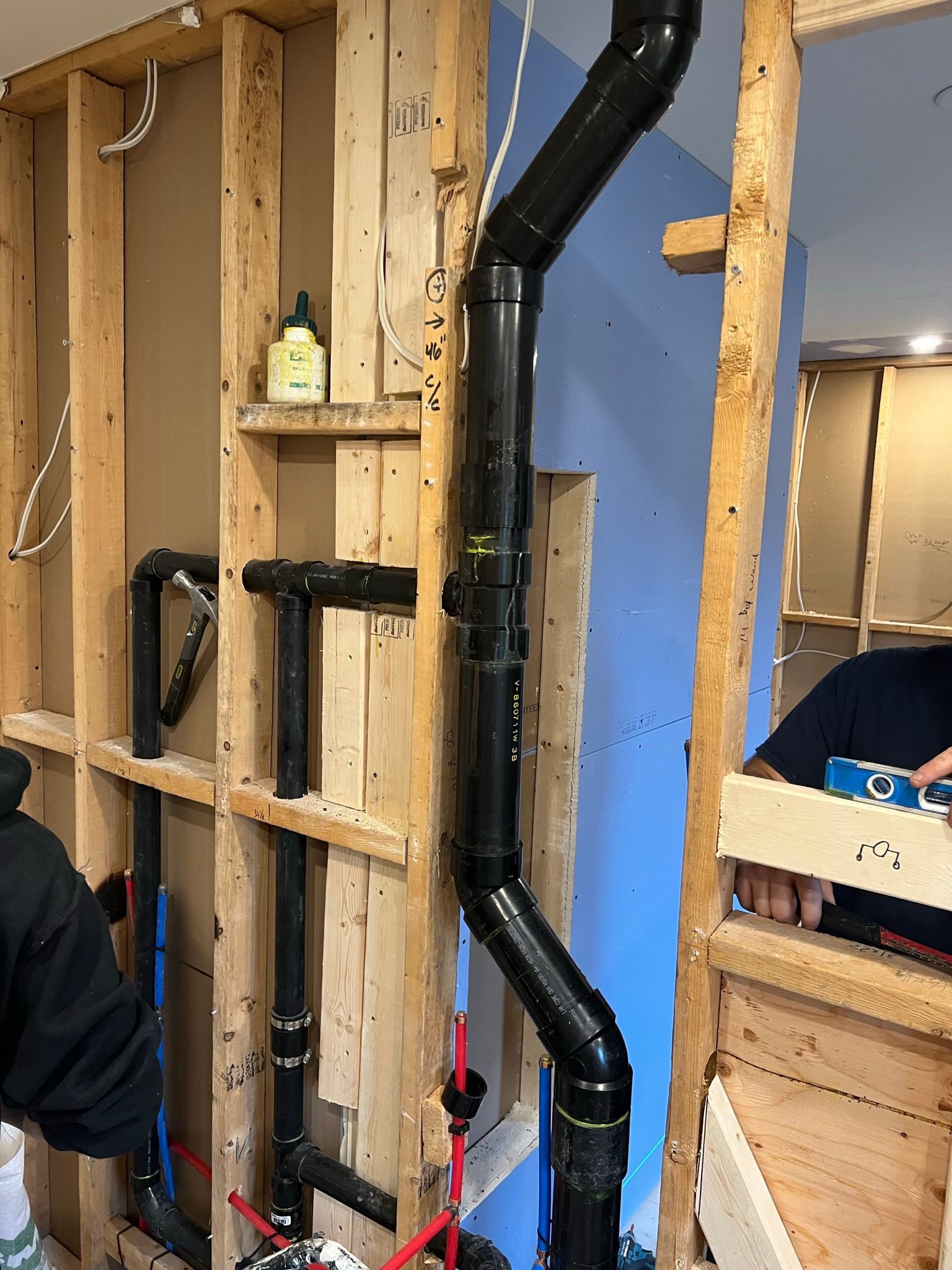 Un homme travaille sur un mur d'où sortent des tuyaux.