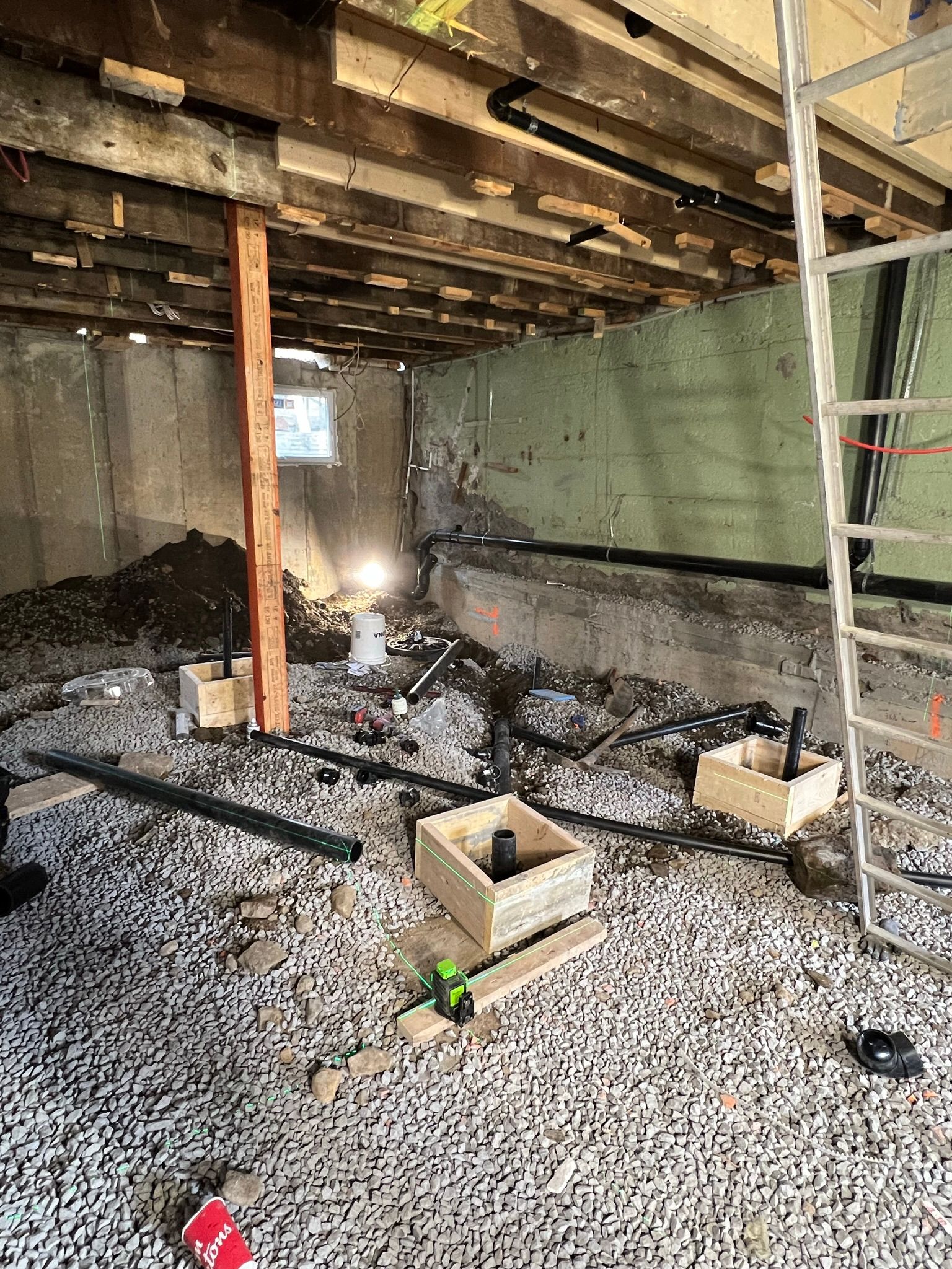 Un sous-sol en construction avec une échelle et des caisses au sol.