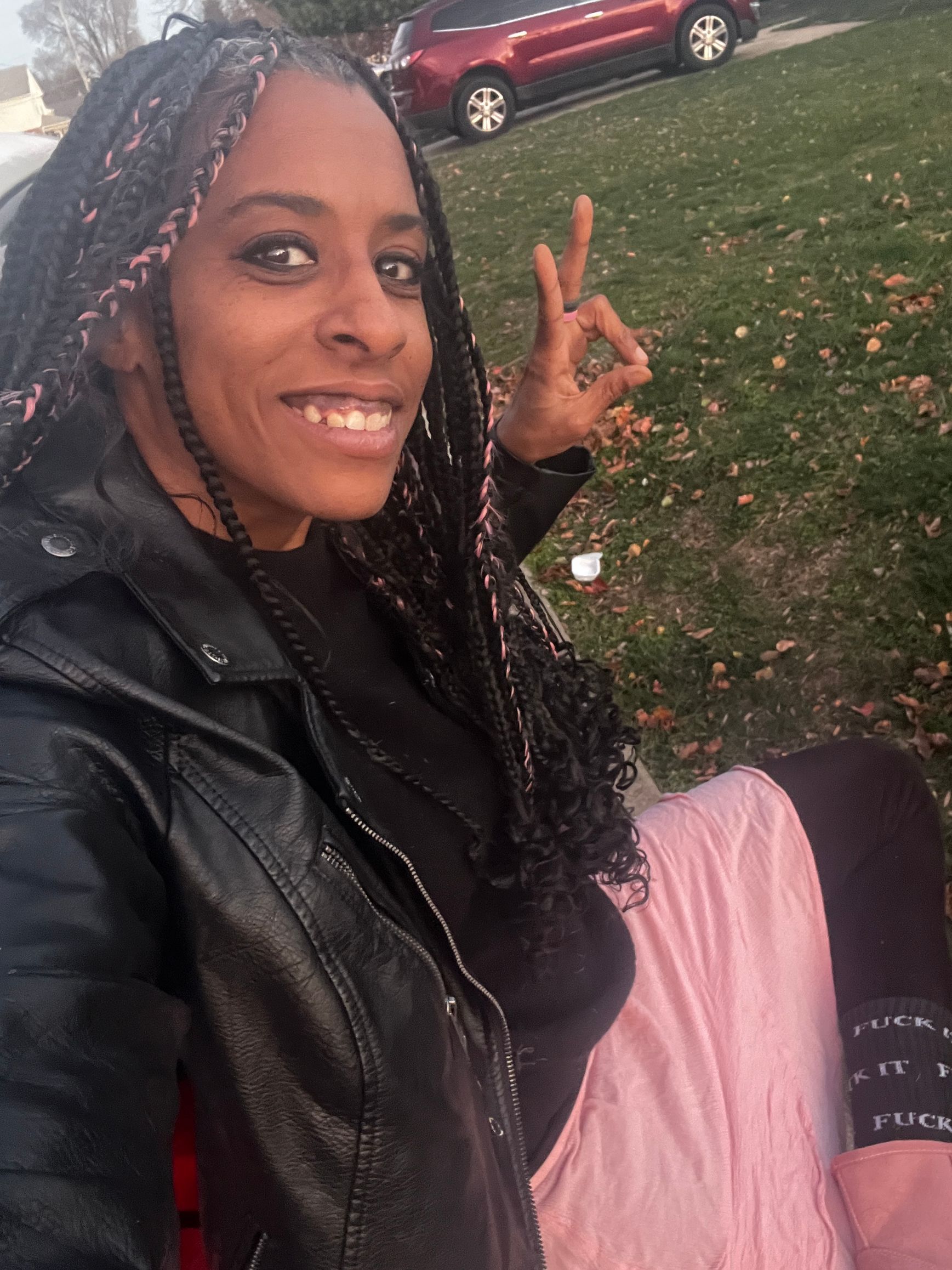 A woman in a black leather jacket is giving a peace sign.